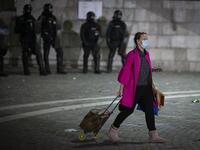 A woman with a shopping trolley walks past police officers wearing anti-riot gear as protesters clash with police during the rally against government’s coronavirus restrictions in Ljubljana on November 5, 2020. Jure Makovec / AFP