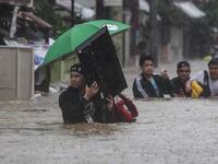 A man (L) carries a television as residents make their way through a flooded street to shelter after Typhoon Vamco hit the area in Marikina City, suburban Manila on November 12, 2020. Ted ALJIBE / AFP