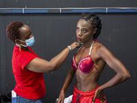 Tan is applied on a bodybuilder before she climbs on stage during the Iron Fit Bodybuilding competition in Nairobi on December 05, 2020. 130 participants from all across East Africa took part in the second edition of this competition which included categories like Bikini, Figure, Physique and Bodybuilding. Patrick Meinhardt / AFP