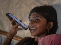 In this photograph taken on October 8, 2020, the daughter of Rohingya refugee Arofa Khatun, who tried to migrate with her two daughters to Malaysia to her husband, speaks on the phone with her father at a makeshift shelter in Kutupalong refugee camp in Ukhia. Stay in a squalid refugee camp -- hopeless, starving, and made to feel a burden -- or leave, risking death, rape, human trafficking and months at sea to reach a husband you've never met. This is the bleak choice many Rohingya women, already scarred fro
