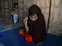 In this photograph taken on October 13, 2020, Rohingya refugee Umme Khair, who gave money to a community leader to travel to Malaysia to her husband, speaks on her mobile phone at a makeshift shelter in Kutupalong Rohingya refugee in Ukhia. Stay in a squalid refugee camp -- hopeless, starving, and made to feel a burden -- or leave, risking death, rape, human trafficking and months at sea to reach a husband you've never met. This is the bleak choice many Rohingya women, already scarred from fleeing persecuti