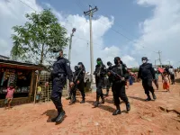 In this photograph taken on October 7, 2020, Rapid Action Battalion (RAB) personnel patrol along a street in Jamtoli refugee camp for Rohingyas in Ukhia. Boatloads of Rohingya landing across Southeast Asia are victims of complex human trafficking networks run by a dizzying web of players, from crime bosses and corrupt cops to poor fishermen, rickshaw drivers and even Rohingya themselves. Munir UZ ZAMAN / AFP