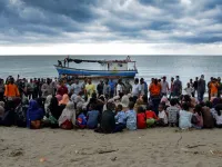 In this file photo taken on June 25, 2020 Rohingya migrants sit by the beach after their boat landed on the shores of Lancok village, in Indonesia's North Aceh Regency. Boatloads of Rohingya landing across Southeast Asia are victims of complex human trafficking networks run by a dizzying web of players, from crime bosses and corrupt cops to poor fishermen, rickshaw drivers and even Rohingya themselves. CHAIDEER MAHYUDDIN / AFP
