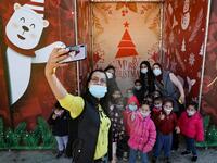 A Palestinian school teacher takes a 'selfie' photograph with her pupils, ahead of Christmas in the biblical city of Bethlehem in the occupied West Bank, amid the novel coronavirus pandemic crisis, on December 19, 2020. Christmas mass in Bethlehem, normally attended by Christian congregations in the West Bank town, will be closed to the public this year due to Covid-19 restrictions, the Palestinian president said earlier this week. The Palestinian Authorities imposed a new lockdown in several governorates i
