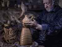Syrian-Armenian potter Misak Antranik Petros uses an ancient pottery wheel to churn different types of pots at his workshop located inside an ancient mud-brick house near the city of Qamishli in Syria's northeastern Hasakeh province, on December 19, 2020. Petros was only a teenager when he had to take over for his sick father and become the main potter of the family. He has since become a master of the craft, and is keen to pass his skills on.  Delil SOULEIMAN / AFP