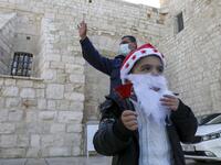 A Palestinian wearing a Santa Claus beard and hat rings a bell outside the Church of the Nativity, in the West Bank city of Bethlehem, on December 20, 2020 after it was re-opened for prayers following strict COVID-19 restrictions. HAZEM BADER / AFP