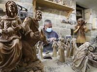 A Palestinian carpenter carves religious statues and figurines from olive wood at a shop near the Church of the Nativity, in the West Bank city of Bethlehem on December 21, 2020. HAZEM BADER / AFP