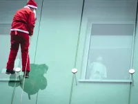 A man dressed as a Santa Claus waves to a child as he descends from the roof of the paediatric clinic in Ljubljana, Slovenia on December 21, 2020. Jure Makovec / AFP