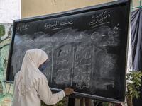 This picture taken during a government-guided tour on December 27, 2020 shows an inmate writing on a blackboard during a literacy class at al-Qanatir women's prison, at the tip of the Nile delta in Qalyoubiya province, about 30 kilometres north of Egypt's capital. Khaled DESOUKI / AFP