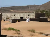 Mohammed al-Ghanbousi, a former inhabitant of Wadi al-Murr, kneels to pray on a sand dune among abandoned houses in the Omani village, about 400 kms (250 miles) southwest of the capital Muscat, on December 31, 2020. MOHAMMED MAHJOUB / AFP