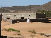 Mohammed al-Ghanbousi, a former inhabitant of Wadi al-Murr, kneels to pray on a sand dune among abandoned houses in the Omani village, about 400 kms (250 miles) southwest of the capital Muscat, on December 31, 2020. MOHAMMED MAHJOUB / AFP