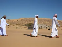 Former inhabitants of Wadi al-Murr, walk near abandoned houses in the Omani village, about 400 kms (250 miles) southwest of the capital Muscat, on December 31, 2020. Encroaching desert sands have left little evidence that Wadi al-Murr ever existed, but former inhabitants, while resigned to its destruction, are trying to preserve its memory. MOHAMMED MAHJOUB / AFP