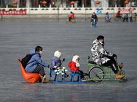 A family uses a sled on a frozen lake in Beijing on January 12, 2021. WANG Zhao / AFP