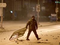 A member of Tunisia's National Guard drags a burning wooden mesh during clashes with protesters in the Ettadhamen city suburb on the northwestwern outskirts of Tunisia's capital Tunis on January 17, 2021, amidst a wave of nightly protests in the North African country. FETHI BELAID / AFP