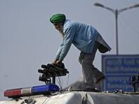 A farmer stands on a police vehicle during a tractor rally as farmers continue to demonstrate against the central government's recent agricultural reforms in New Delhi on January 26, 2021. Money SHARMA / AFP