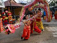 This photograph taken on January 21, 2021 shows Le Yen Quyen (C) of the Tu Anh Duong lion and dragon dance school performing a dragon dance outside a newly-opened cafe in Can Tho city in southern Vietnam's Mekong Delta. Manan VATSYAYANA / AFP