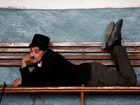 In this picture taken on February 9, 2021, street actor Usman Khan, dressed up as silent film star Charlie Chaplin, performs at a train station in the Pakistan's northwestern city of Peshawar. Wearing a bowler hat and familiar toothbrush moustache, Pakistan's Usman Khan darts through traffic swinging a cane, teasing motorists and shopkeepers for laughs and a few rupees with a Charlie Chaplin impersonation that has become a viral sensation.  Abdul MAJEED / AFP