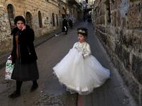 An Ultra-Orthodox Jewish child dressed in a bride's to celebrate Purim walks in the street a day ahead of the official holiday, in the Mea Shearim neighbourhood in Jerusalem, on February 24, 2021. The carnival-like Purim holiday is celebrated with parades and costume parties to commemorate biblical story of the deliverance of the Jewish people from a plot to exterminate them in the ancient Persian empire , as recorded in the Book of Esther. MENAHEM KAHANA / AFP