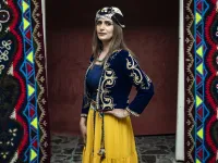 A Syrian Kurdish woman in traditional attire poses for a picture 