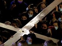 Christian worshippers carrying a wooden cross walk inside the Church of the Holy Sepulchre,