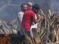 A man reacts as he performs the last rites of his relative amid the funeral pyres of victims who died of the Covid-19 coronavirus during mass cremation held at a crematorium in New Delhi 