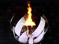 Japanese tennis player Naomi Osaka holds the Olympic Torch after lighting the flame of hope in the Olympic Cauldron during the opening ceremony of the Tokyo 2020 Olympic Games, at the Olympic Stadium, in Tokyo