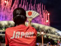 A Japanese supporter looks on as fireworks light up the sky over the Olympic Stadium during the opening ceremony of the Tokyo 2020 Olympic Games,