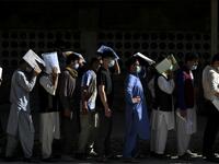 People stand in a queue to submit their passport applications at an office in Kabul on July 25, 2021. Dozens begin lining up at the passport office in Kabul before dawn most days, and by eight in the morning the queue already stretches for a good hundred metres. 