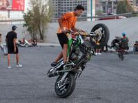 Iraqi youths perform stunts on motorbikes and scooters in the Jadriya district of Baghdad on August 6, 2021. All dressed up and nowhere to go: many young Iraqis in Baghdad make an effort to be hip, even as they admit their country may have no future. 