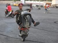 Iraqi youths perform stunts on their scooters in the Jadriya district of Baghdad on August 6, 2021. All dressed up and nowhere to go: many young Iraqis in Baghdad make an effort to be hip, even as they admit their country may have no future.
