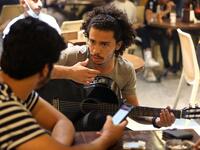 Iraqi guitarist Mohammed, 23, plays as he sits with his friends at a coffee shop in the Karrada district of the capital Baghdad, on August 6, 2021. All dressed up and nowhere to go: many young Iraqis in Baghdad make an effort to be hip, even as they admit their country may have no future. 