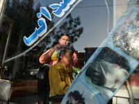 In this picture taken on September 19, 2021, 24-year-old Nader Shah (L) attends a customer at his barbershop in Herat. Quiffs, mohawks, and crew cuts were hairstyles Shah was accustomed to styling for image-conscious young men in Afghanistan’s third-biggest city of Herat.  