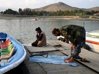 Taliban fighters offer prayers on a dock for boats at Qargha Lake on the outskirts of Kabul. "This is Afghanistan!" a Taliban fighter shouts on the pirate ship ride at a fairground in western Kabul, as his armed comrades cackle and whoop on board the rickety attraction. (Photo by WAKIL KOHSAR / AFP) / TO GO WITH: AFGHANISTAN-CONFLICT-FAIRGROUND, SCENE BY JAMES EDGAR - TO GO WITH: Afghanistan-conflict-fairground, SCENE by James EDGAR