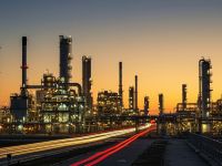 صورة خارجية لمنشأة طاقة صناعية مستقبلية عند غروب الشمس، تُظهر مصفاة نفط متقدمة بتفاصيل معقدة.