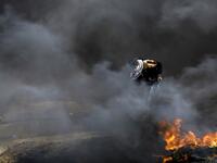A Palestinian protester runs for cover amidst the fumes from burning tires during clashes with Israeli forces across the border, following a demonstration calling for the right to return.
(MOHAMMED ABED / AFP)