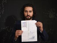 In this photo taken on October 8, 2018, Afghan co-founder and president of ArtLords Omaid Sharifi, 32, poses for a picture as he holds his id card or Tazkira registered to vote in the upcoming parliamentary election, in Kabul. 
WAKIL KOHSAR / AFP