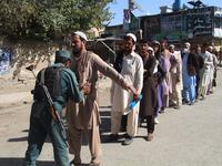 An Afghan policeman searches voters before casting their votes at a polling centre for the country's legislative election in Khost Province on October 20, 2018. 
FARID ZAHIR / AFP