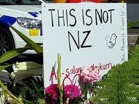 A message is seen as residents pay their respects by placing flowers for the victims of the mosques attacks in Christchurch 
Glenda KWEK / AFP