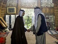 Members of an Iraqi clan shake hands as they meet inside a straw tent in the town of Mishkhab, south of Najaf on November 15, 2018. 
Haidar HAMDANI / AFP