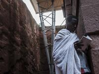 An Ethiopian Orthodox devotee reads a bible near the pillar of a shelter protecting from erosion the rock-hewn structure of the church of Saint Emmanuel in Lalibela, Ethiopia
EDUARDO SOTERAS / AFP