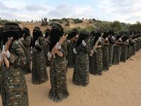 The camouflage wearing women of the outfit stand in line holding wooden rifles.  al-Quds Brigades is the military wing of Islamic Jihad, the second-most powerful armed group in the Gaza Strip after Hamas (APA)