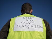 A man wears a yellow vest with the inscription "Stop to French taxes" while protestors slow down traffic on a road in Saint-Herblain, near Nantes, western France.
SEBASTIEN SALOM GOMIS / AFP