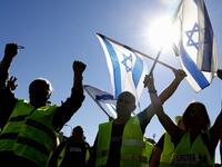 Israeli protesters wearing a yellow vest carry national flags during demonstrations against the rising cost of living on December 14, 2018, in the Israeli coastal city of Tel Aviv. 
JACK GUEZ / AFP
