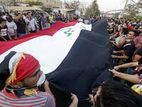 Iraqi protesters chant slogans and wave a large national flag as they gather in a demonstration against corruption and lack of basic services outside the local government headquarters in the southern city of Basra on September 2, 2018. 
Haidar MOHAMMED ALI / AFP
