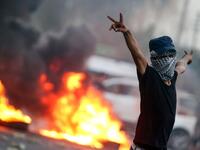 A masked Iraqi protester gestures while standing before burning tires during clashes with security forces in the southern city of Basra on September 2, 2018. 
Haidar MOHAMMED ALI / AFP