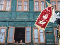 Kashmiri muslim family watches from a window of a residential house as Kashmiri Shiite Muslim mourners flagellate themselves during a religious procession.Tauseef MUSTAFA / AFP