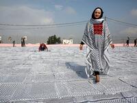 Palestinian Southern Education Direction's member Safa'a Amro (R) prepares a one thousand four hundred Meter square Keffiyeh. (HAZEM BADER / AFP)