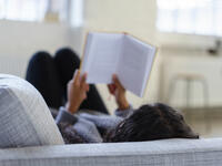 woman reading book couch