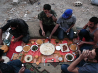 Fighters from the Syrian army gather for a simple Iftar dinner. Inflation and extremely high food prices have made it costly for many people to afford Iftar meals. Often, families cannot afford dates and milk to break their fast. Many also live without the traditional sweets, due to the skyrocketing prices for sugar. 
