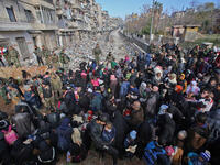 Aleppo’s exodus: Syrian residents fleeing violence gather at a checkpoint, manned by pro-government forces, in the Maysaloun neighborhood of Aleppo on December 8, 2016. 